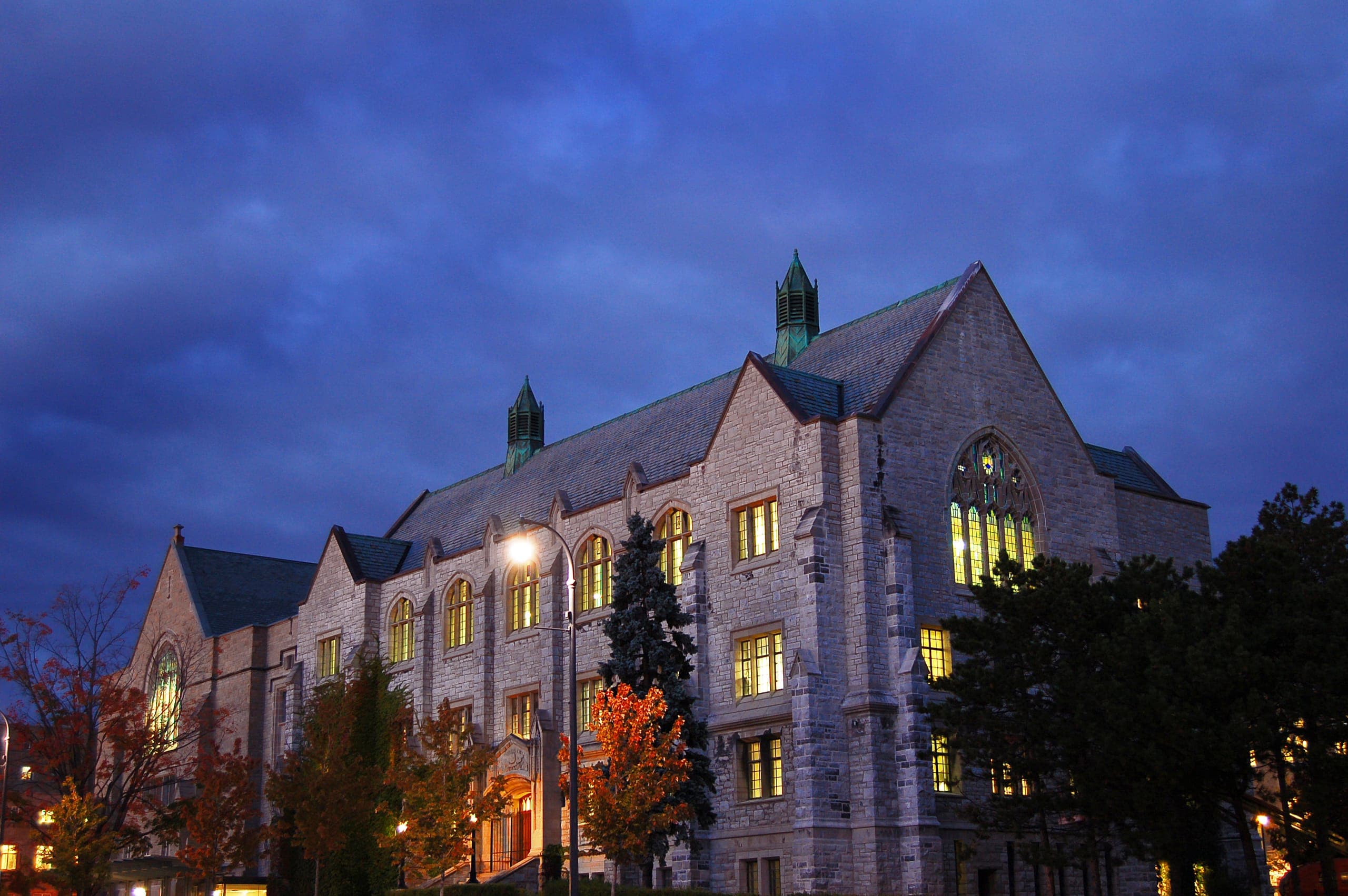 Douglas Library at Queen's University at dusk, its windows lit